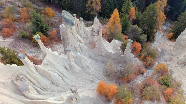 4k drone flying over footage (Ultra High Definition) of Earth pyramids of Platten - Spiky sand towers formed by water erosion and accessed by a woodland trail dotted with sculpture.