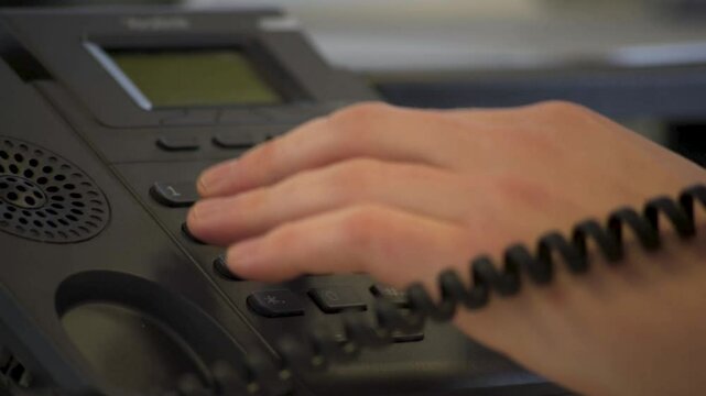 Vertical Close-Up of Hand typing buttons on work phone