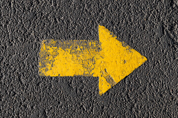 The yellow arrow is painted on the surface of the asphalt with a thick layer of paint. Top view.