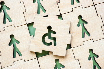 Puzzle close-up with figurines and disability person sign. Inclusion and accessibility.