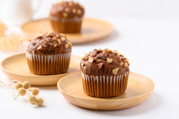 Chocolate almond muffin on wooden plate with white background