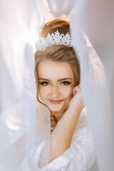 A woman is wearing a tiara and is smiling. She is looking at the camera. The photo is blurry and...