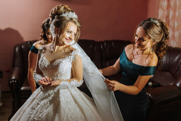 A bride is getting ready for her wedding and her bridesmaid is helping her with her veil