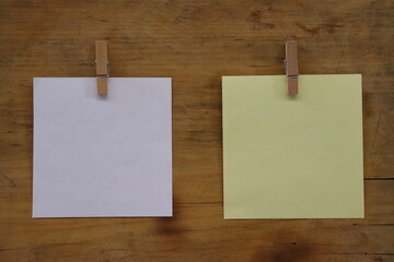 Blank sheet of paper with clothespin hanger, light brown wooden background.