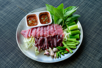 Thai menu close-up, beef sashimi meat - raw beef slice on plate with fresh vegetables and spicy sauce, Fresh raw beef.esan beef, esan food,