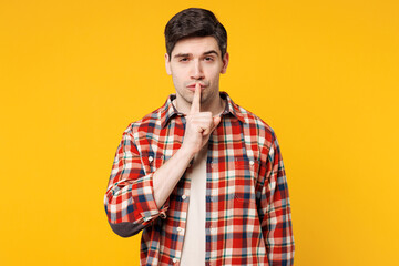 Young secret happy Caucasian man wears red checkered shirt casual clothes say hush be quiet with...
