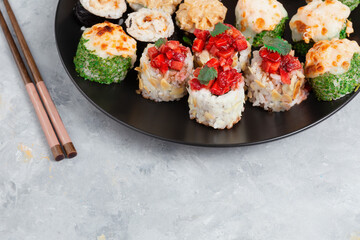 Assorted Sushi Rolls On Black Plate With Chopsticks