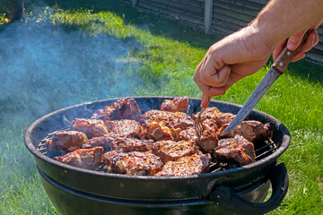 man cooking meat on the grill on a barbecue on a sunny day.Holiday Family weekends and rest