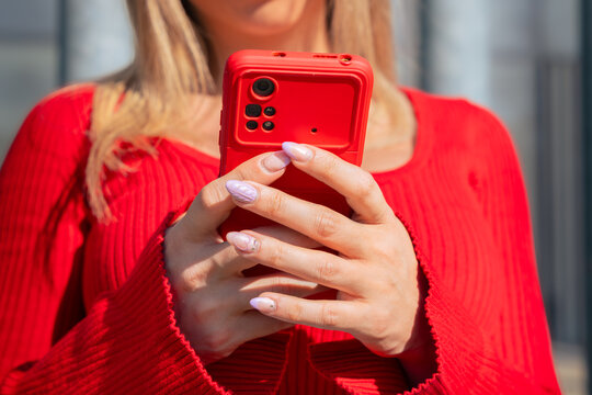 Glamorous smiling woman, sitting using a social media app on a smartphone.