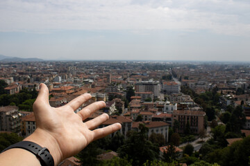 An outstretched hand against a panoramic view of a cityscape with terracotta rooftops, urban...