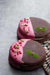 Chocolate cookies with cream and pink glaze on gray background