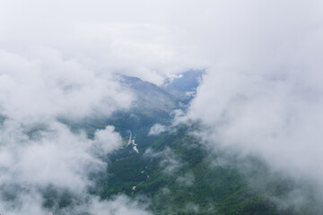 aerial view of wild forested mountain slope through clouds