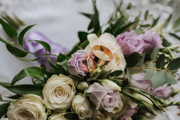 A bouquet of flowers with a gold ring in the middle. The ring is surrounded by white flowers and...