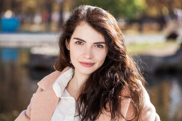 Portrait of a young beautiful brunette woman in autumn park