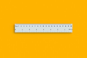 Ruler with inches and centimeters on orange background. School equipment. Measuring tool. Top view. 3d render