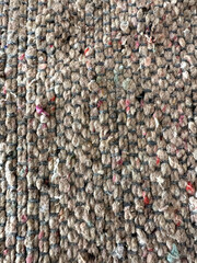 Textured carpet with a woven pattern, featuring shades of brown and red.