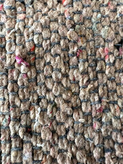 Textured carpet with a woven pattern, featuring shades of brown and red.