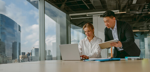 A team of professionals discusses innovative strategies in a spacious office with stunning city...
