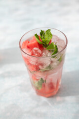 Homemade summer watermelon lemonade with ice and mint on light background, place for text