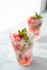 Homemade summer watermelon lemonade with ice and mint on light background, place for text