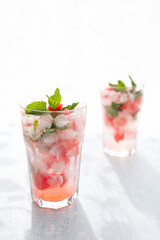 Homemade summer watermelon lemonade with ice and mint on light background, place for text