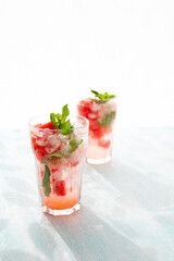 Homemade summer watermelon lemonade with ice and mint on light background, place for text