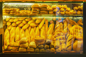Bakery showcases a variety of fresh bread and pastries, warm, golden illuminating of shelves