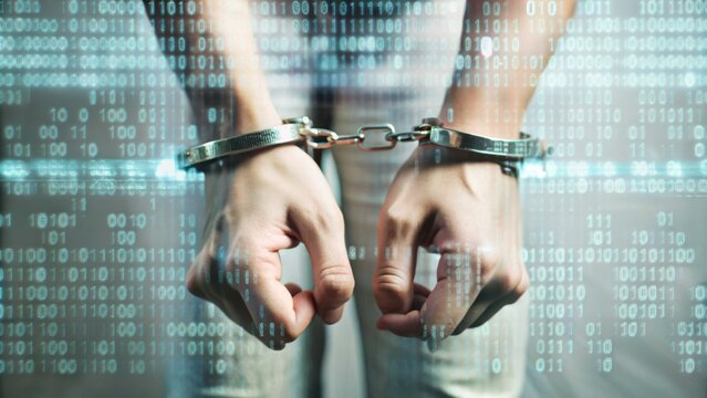 A man in a black turtleneck is handcuffed with handcuffs. Concept of an arrest for breach of cyber security.