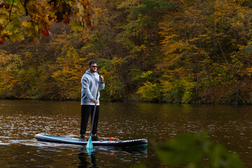 Man Paddleboarding in Autumn Lake