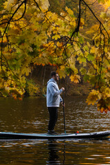 Man Paddleboarding in Autumn Lake