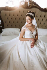 A woman in a wedding dress is sitting on a bed