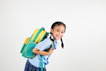 Portrait smile Asian little girl kindergarten holding a green and yellow backpack posing studio isolated white background, happy cute woman kid wear school uniform plaid skirt, back to school concept