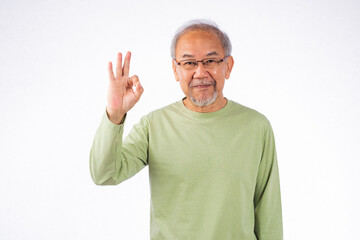 Portrait Asian senior man with glasses and a green shirt showing OK sign studio shot isolated on white background. Concept of approval and positivity, old man smiling