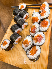 Someone picking salmon sushi roll or sake maki using chopsticks on Japanese Restaurant. Concept for whole healthy food, nutrition, omega-3, animal protein, seafood, modern resto and street food.