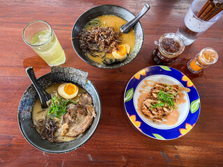 Japanese pork miso ramen consisting of broth, miso, pork, sliced scallions, sliced mushrooms, soft half boiled egg or ajitsuko tamago ajitama in a bowl on a wooden table.