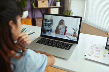 Person participating in virtual learning session observing tutor on laptop screen holding color...