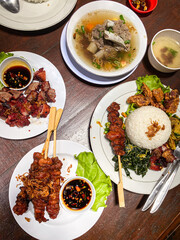 Nasi Campur Bali or Balinese mixed rice with various side dish on white ceramic plate. Authentic Balinese Food with a lot of spices and variation menu.