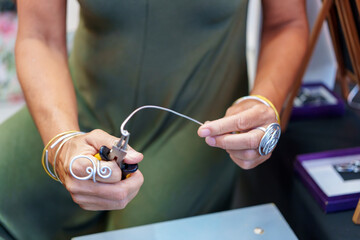 Unrecognizable Hispanic Woman in Her 50s Crafting Earrings at Her Street Stall Selling Handmade Aluminum Wire Jewelry 