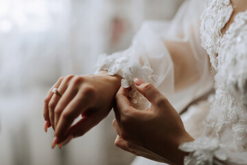 A woman is wearing a white dress and is adjusting her wedding ring. Concept of elegance and sophistication, as the woman is getting ready for a special occasion. The focus on her hands