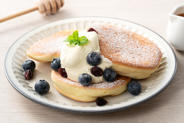 Delicious Japanese souffle pancake with blueberry, cranberry and honey on wooden table background.