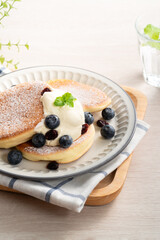Delicious Japanese souffle pancake with blueberry, cranberry and honey on wooden table background.