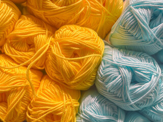 multiple wool thread yarn balls in yellow and baby blue, full frame, close up, high angle view