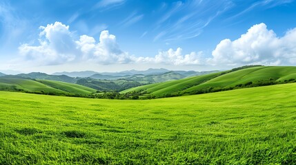 Fototapeta premium A scenic landscape of lush green hills under a bright blue sky with fluffy clouds, capturing the beauty of nature's tranquility.