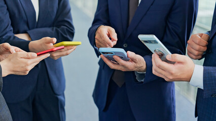 スマホを使うビジネスパーソンのグループ © metamorworks