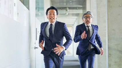オフィスを二人で走るビジネスパーソン