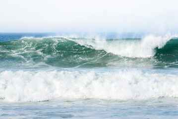 Pacific ocean waves breaking on the shore sending up plumes of spray on a windy autumn day