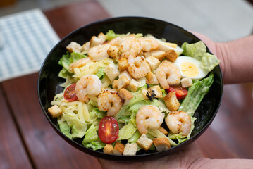 Casear salds with prawns home made tasty holding hand