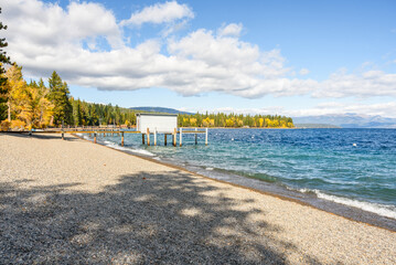 Empty pebble beach with wooden piers and boathouses  on a lake on a sunny autumn day