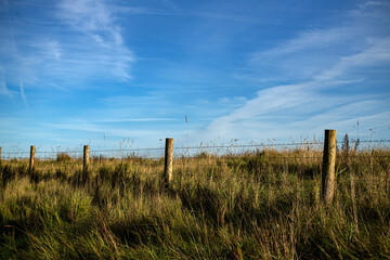 Obraz premium Fenced off. Wire fence on the estuary at Fremington in North Devon. Beautiful summer day with a cloudy blue sky.