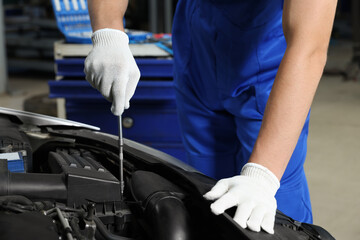 Auto mechanic fixing car at automobile repair shop, closeup